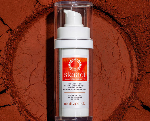 skaadi® Muttererde Elementra Spätsommerserum liegt auf rotbraunem pudrigen Untergrund mit Rissen