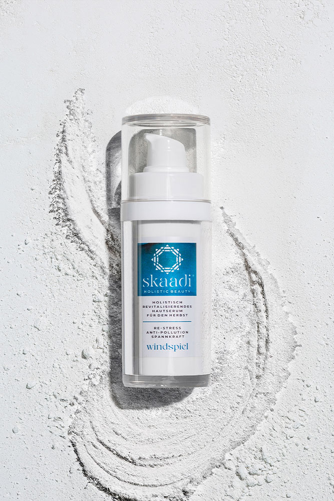 skaadi® Windspiel Elementra Herbstserum liegt auf weißem pudrigen Hintergrund