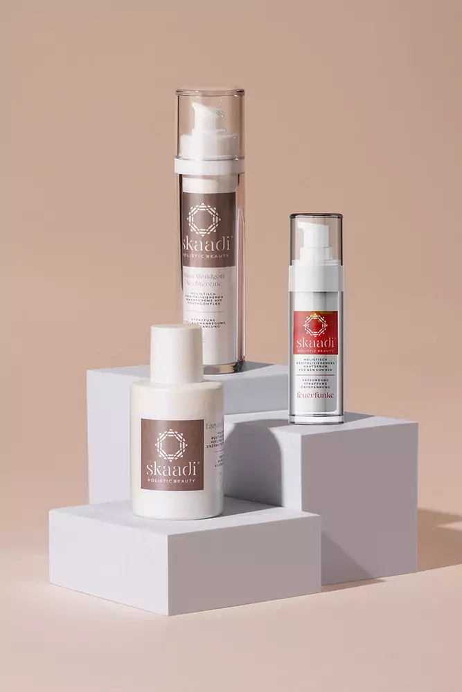 Alle im Glow Bundle enthaltene Produkte auf unterschiedlich großen weißen Quadraten platziert: Máni Mondgott Nachtcreme, Enzym Peel Powder, Feuerfunke